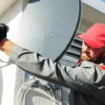 un tecnico antennista monta un'antenna parabolica