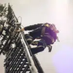 antennista si arrampica su un una parabola con tutti i dispositivi di sicurezza